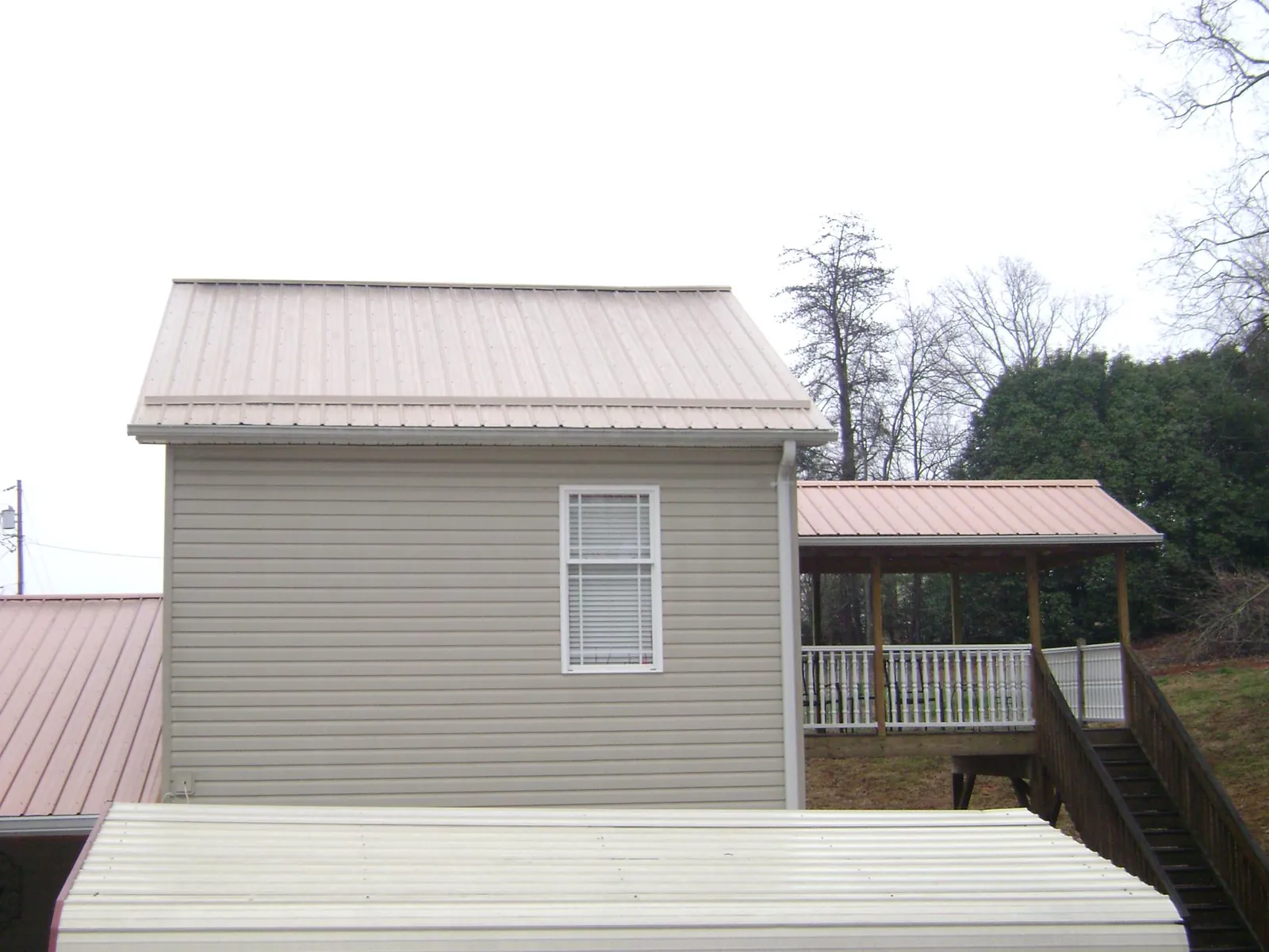 Tan metal roofs on a two story addition and attached porch, from a Roof Replacement job in Dayton